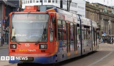 Sheffield Supertram heading up High Street towards Middlewood from Sheffield city centre with Fargate and Cutler's Hall to the left