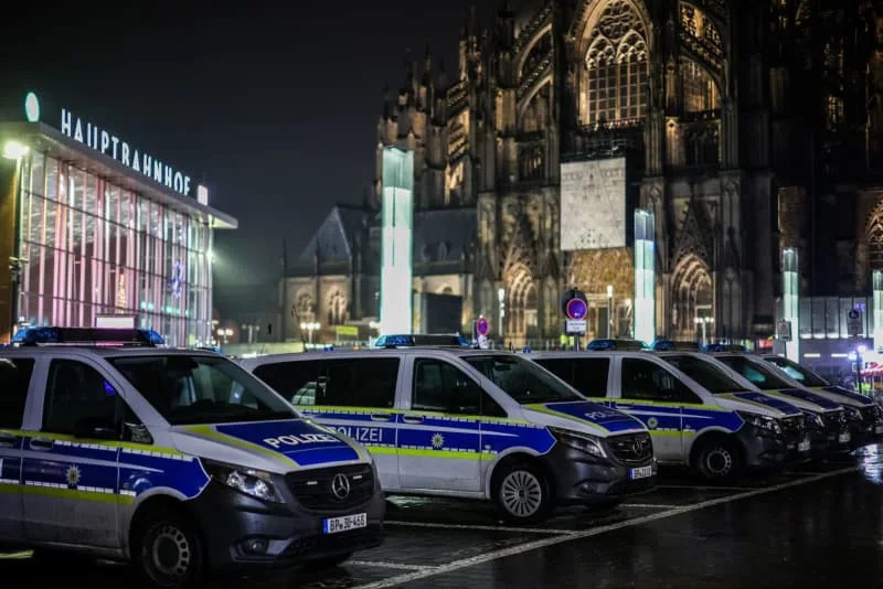 Police vehicles park in a parking lot at the exit of the main train station near Cologne Cathedral. Christoph Reichwein/dpa