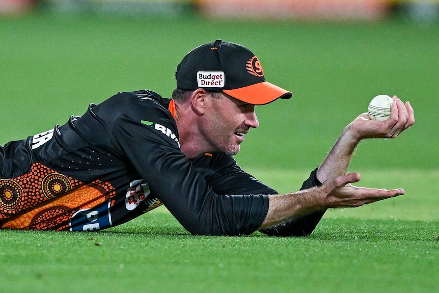 Perth Scorchers player Ashton Turner makes sure to hold the ball above the grass after a BBL catch.