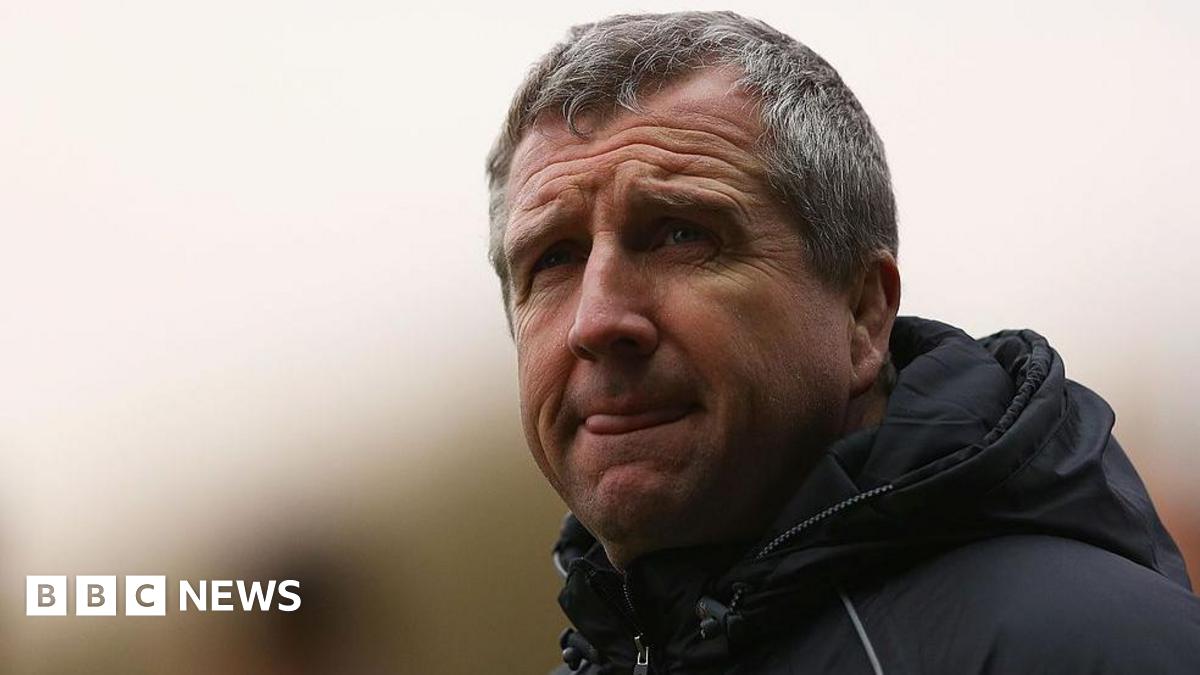A grey haired man in a black coat, with a look of concentration staring off into the distance.