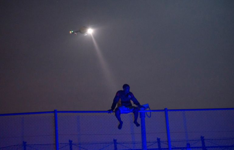REUTERS PICTURES 40th ANNIVERSARY COLLECTION: An African migrant sits on top of a border fence covered in razor wire between Morocco and Spain's north African enclave of Melilla, during a latest attempt to cross into Spanish territory, June 14, 2014. REUTERS/Jesus Blasco de Avellaneda SEARCH "REUTERS PICTURES 40th ANNIVERSARY COLLECTION" FOR THIS PACKAGE