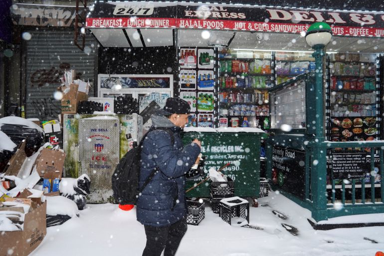 A person walks past a deli in snowy weather