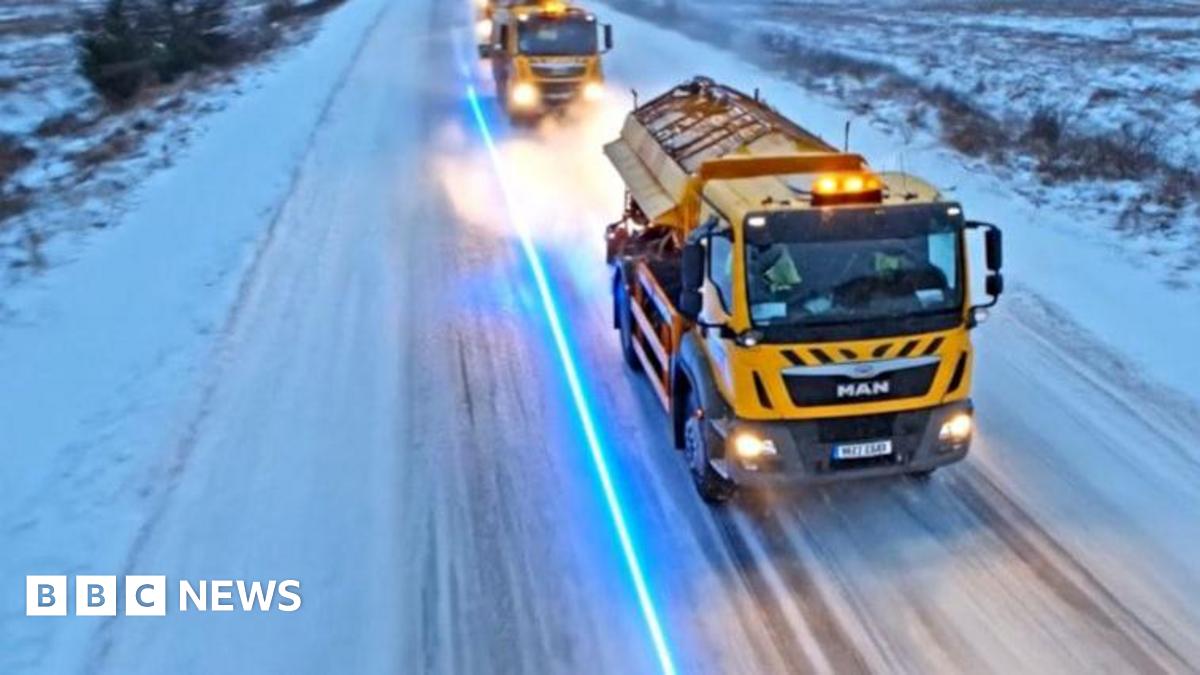 Yellow gritters travelling down a road in Lancashire covered in snow and ice.