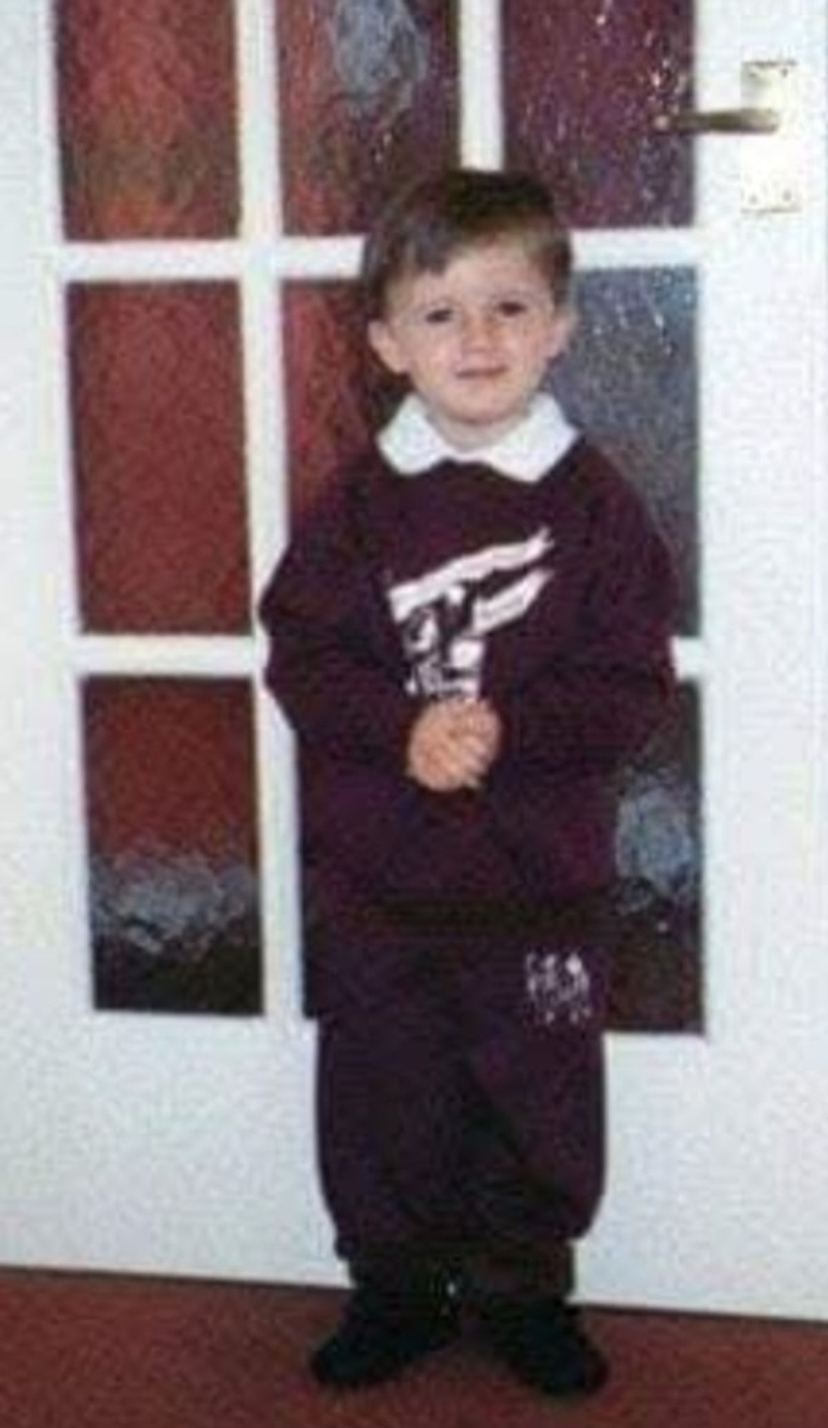 A schoolboy poses in St Cecilia's Catholic Primary School uniform on his first day of school.