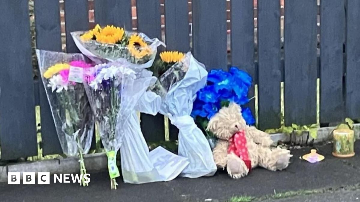 Floral tributes and a teddy bear left outside a house