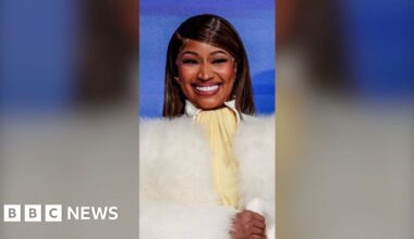 A woman, Nicki Minaj, smiling wearing a fluffy white jacket.
