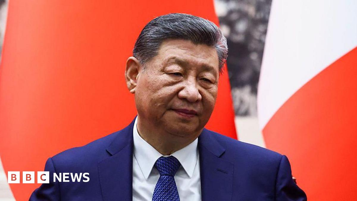 Chinese President Xi Jinping attends a signing ceremony for agreements at the Great Hall of the People in Beijing on December 4, 2025. He is wearing a dark blue sit and in front of a red and white background.