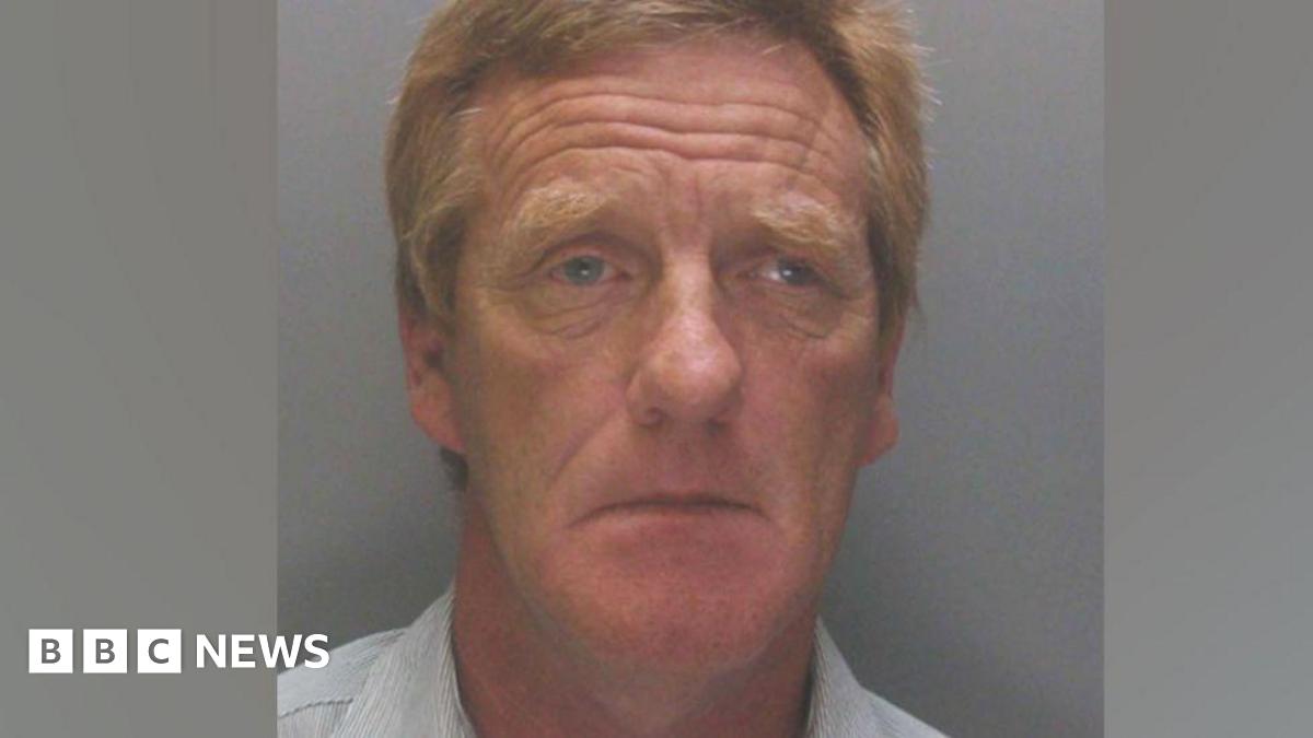 A police mugshot of Anthony Burns, 63, who has ginger hair and is wearing a light blue collared shirt. He is looking into the camera with a sorrowful expression.