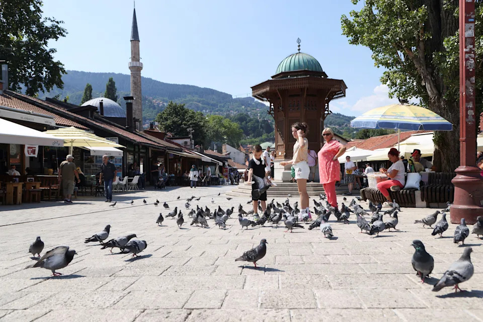 Tourists feed pigeons amid a heatwave, in Sarajevo, Bosnia and Herzegovina, Aug. 13, 2024.