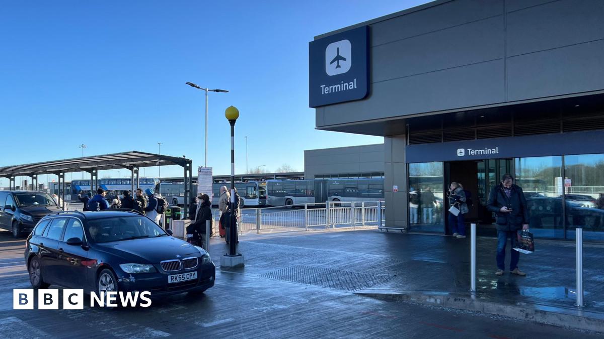 Bristol Airport drop-off parking, with a car in the foreground and people queuing up behind. Signs for the terminal can be seen at the top