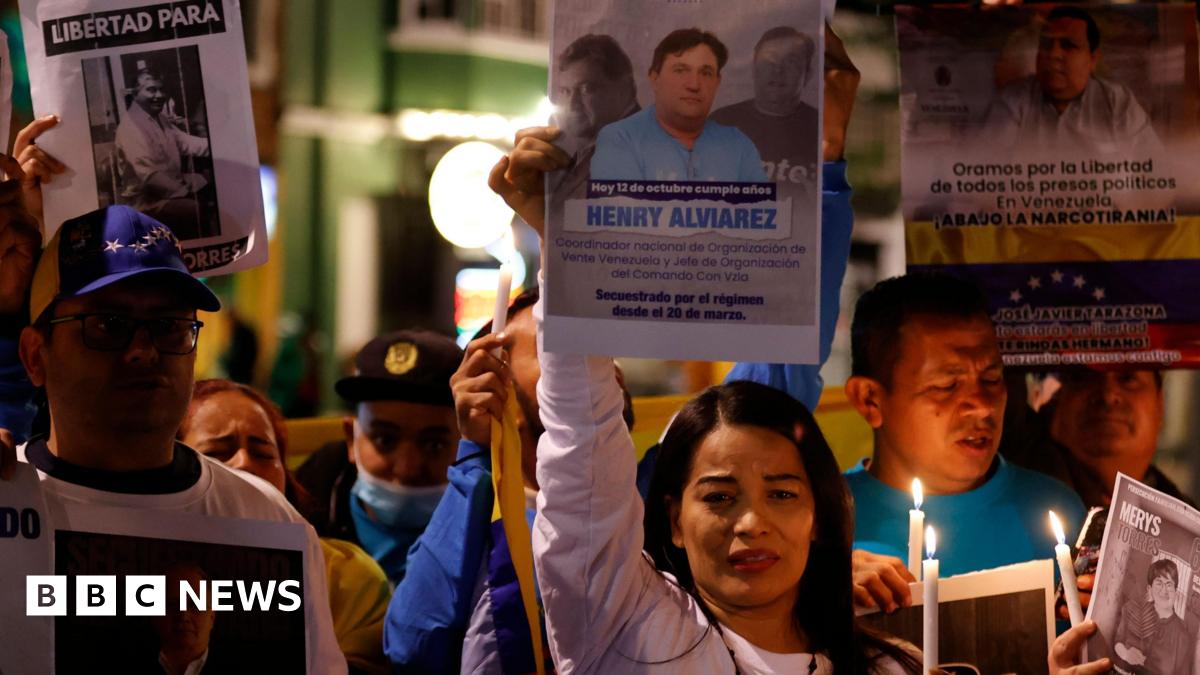 A group of protesters with a woman centred hold candles and signs of people who have been made political prisoners in Venezuela