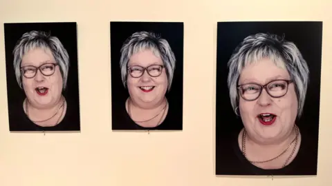 Three pictures of the same woman with short grey and black choppy hair. She is wearing glasses and has red lipstick on. She is wearing a black top and a silver chain. She looks happy in all three of them.