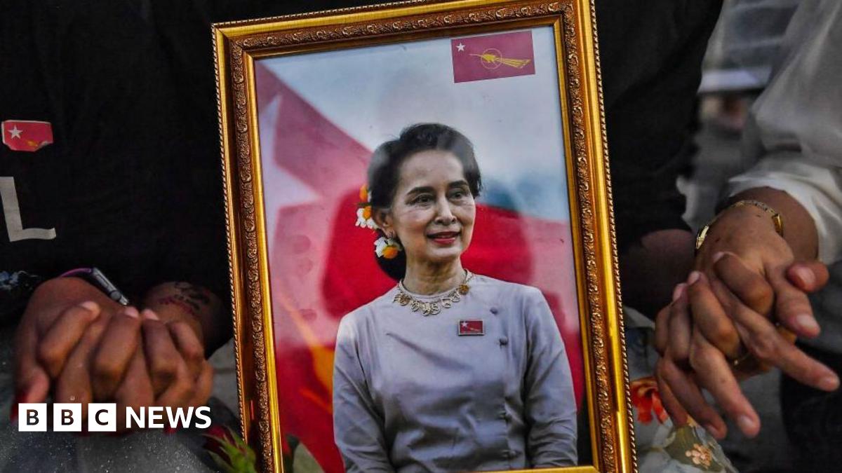 A picture of detained civilian leader Aung San Suu Kyi is seen as Myanmar migrants living in Thailand hold hands during a memorial in Bangkok on March 4, 2021 to honour those who died during demonstrations against the military coup in their homeland.