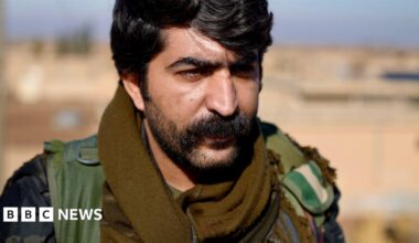 Kurdish soldiers stand on a wall with their weapons in hand