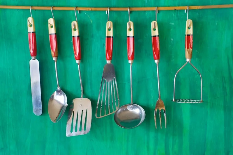 vintage kitchen utensils on green painted wall, free copy space