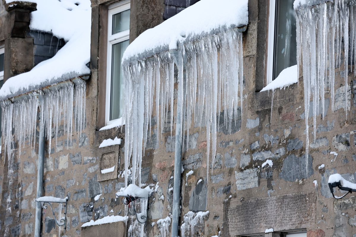 A picture of Icicles hang on the edge of a house