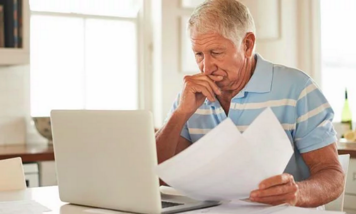 An older man is looking at a form he needs to complete. 