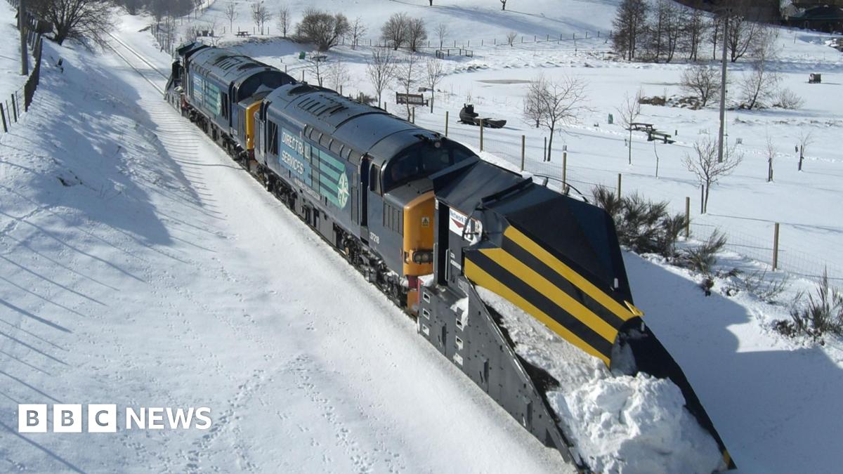 A train with a snow plough attached trundling through a snow-bound landscape