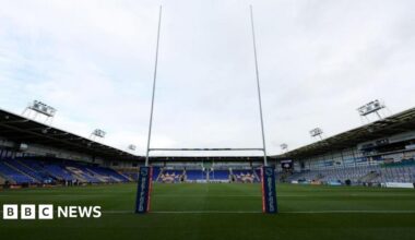 The inside of the Halliwell Jones Stadium, with pitch and goalposts and tiered seating in view.