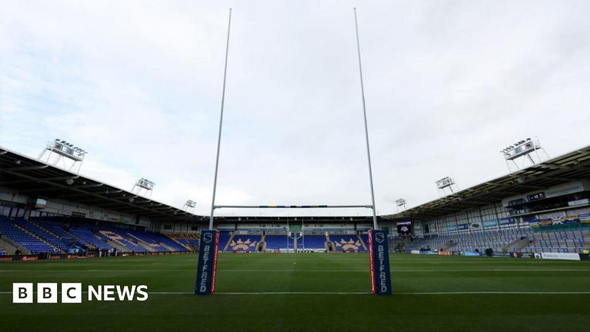 The inside of the Halliwell Jones Stadium, with pitch and goalposts and tiered seating in view.