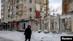 A woman on December 31 walks past an apartment building that was hit by a Russian missile earlier in 2025 in Kyiv.