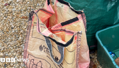 Faded red North Somerset recycling bag, with holes along the top seam.