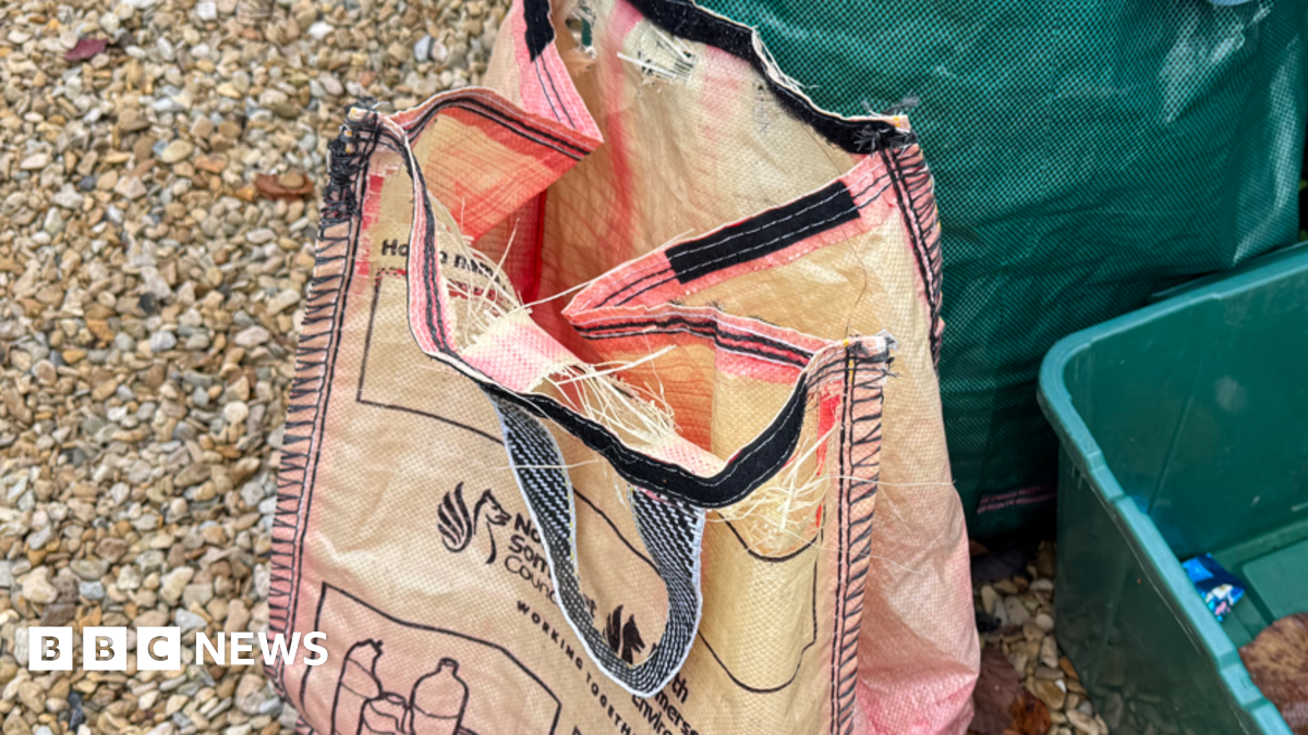 Faded red North Somerset recycling bag, with holes along the top seam.