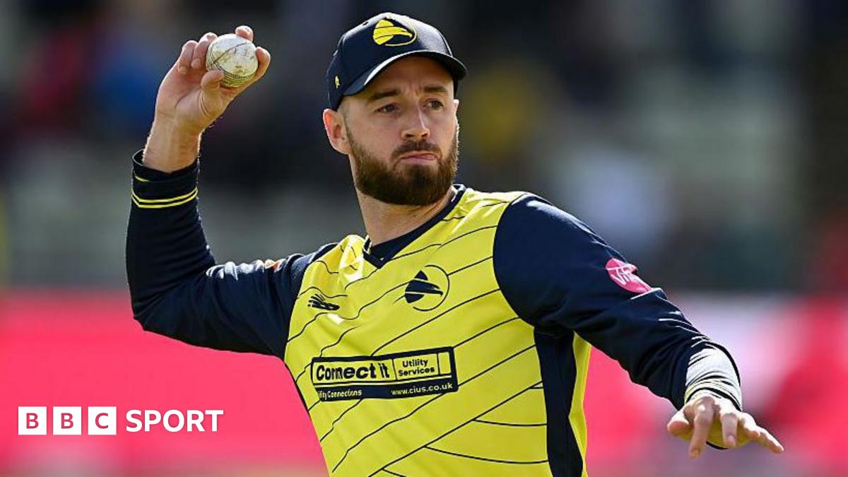 James Vince shapes to throw a white cricket ball, dressed in Hampshire Hawks' yellow shirt with thin, navy blue diagonal stripes and navy blue sleeves
