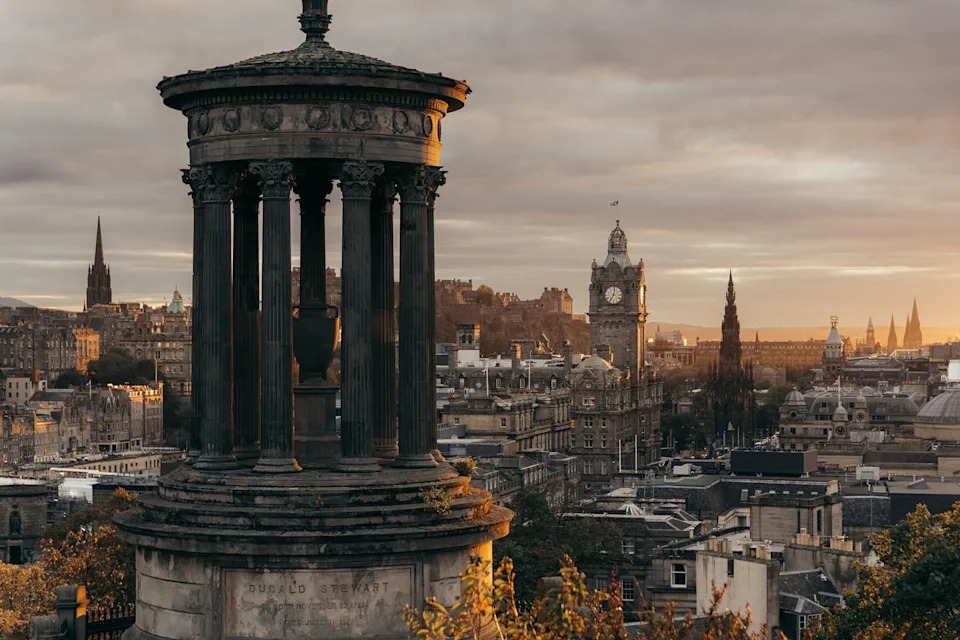A cityscape viewed from a hilltop with an old stone pagola in the foreground.
