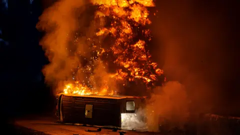 ITV A coach on its side on fire, with huge flames rising into the night sky, in a scene from Corriedale