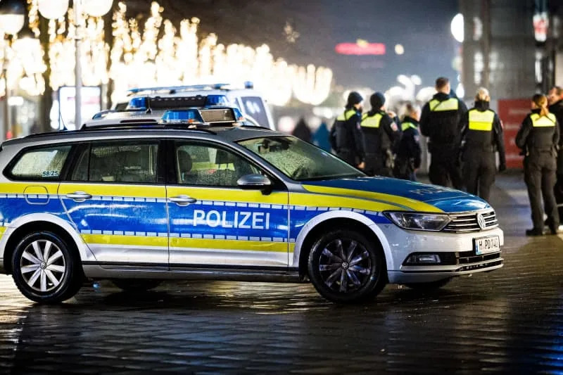 Emergency vehicles and police officers stand in the city center on New Year's Eve in rainy weather. Moritz Frankenberg/dpa