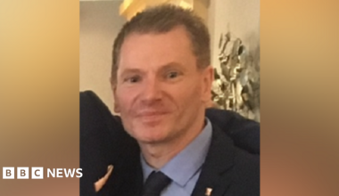 Gary McMahon - a man with light coloured spiked hair and wearing a dark suit, with blue shirt and dark tie - smiling for a photo.