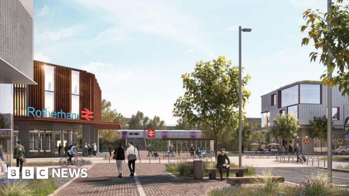 Miracle Moyo stands against a grey background, she is smiling and wears her long black hair in plaits held back with a black hair band.  A grey hoodie is visible under her cream coloured woolly fleece jacket.