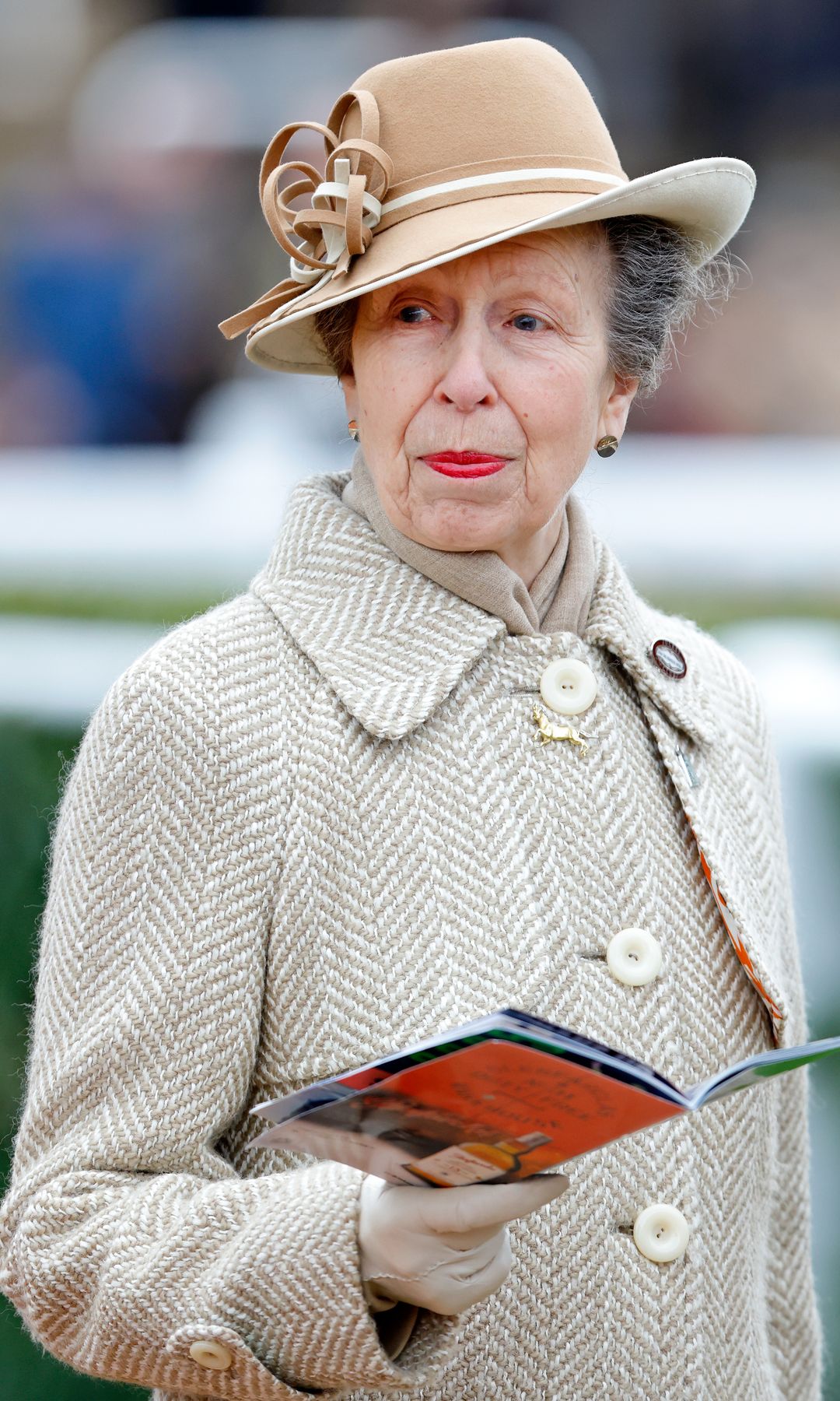 Princess Anne holding booklet in neutral hat and coat