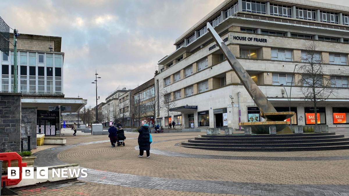A general view of Plymouth City Centre. The sundial is on the right and there's people stood nearby. The toilet blocks are to the left.