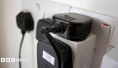 Close-up of a UK electrical plug socket with several devices plugged in.