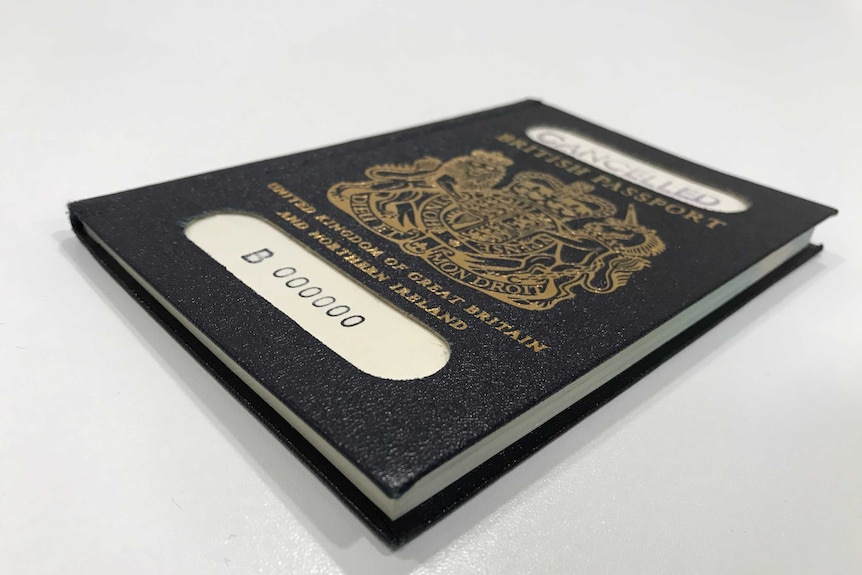 A blue British passport with white sticker saying cancelled.