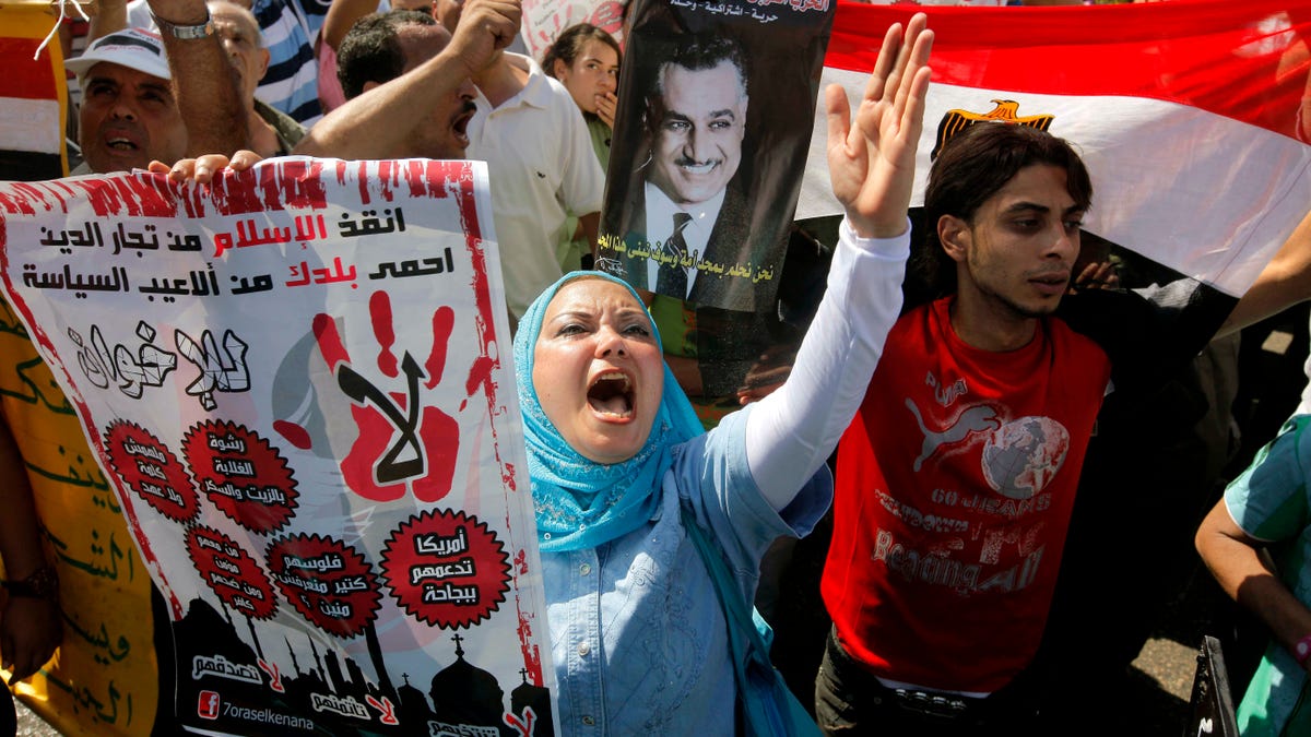 Egyptian anti-Muslim Brotherhood protesters shout slogans and hold posters of the late President Gamal Abdel Nasser during a rally to denounce the country's Islamist President Mohammed Morsi and his Muslim Brotherhood group in Cairo, Egypt, Friday, Aug. 24, 2012. Friday's protests were the first attempt by Morsi's opponents to stage a major demonstration against the new president. Arabic reads " no to Muslim brotherhood, save Islam from religion traders, and save your country." (AP Photo/Amr Nabil)