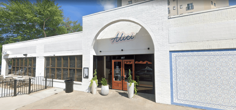 Alici restaurant exterior with white brick facade, arched entrance, wooden doors, and decorative tile wall in downtown area