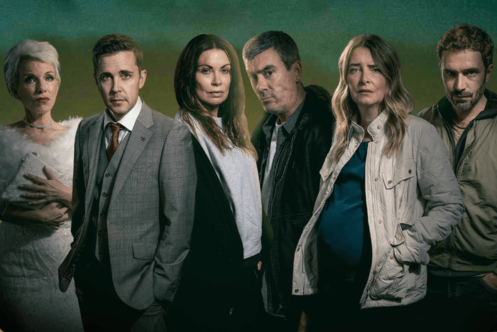 An image depicting a nighttime scene on a road with car headlights in the distance, from left to right we see Sue Devaney as Debbie Webster in a wedding dress, Gareth Pierce in a suit as Todd Grimshaw, Alison King as Carla Connor with a bloodied forehead, Jeff Hordley as Cain Dingle, Emma Atkins as a pregnant Charity Dingle, and Oliver Farnworth as a brooding John Sugden, in a promo image for Corriedale.