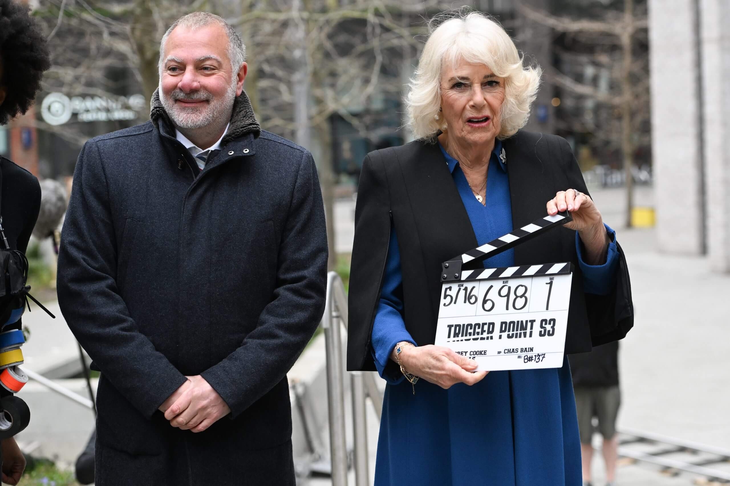 Jed Mercurio alongside the real Queen Camilla, holding a clapper board, on set of his TV drama Trigger Point