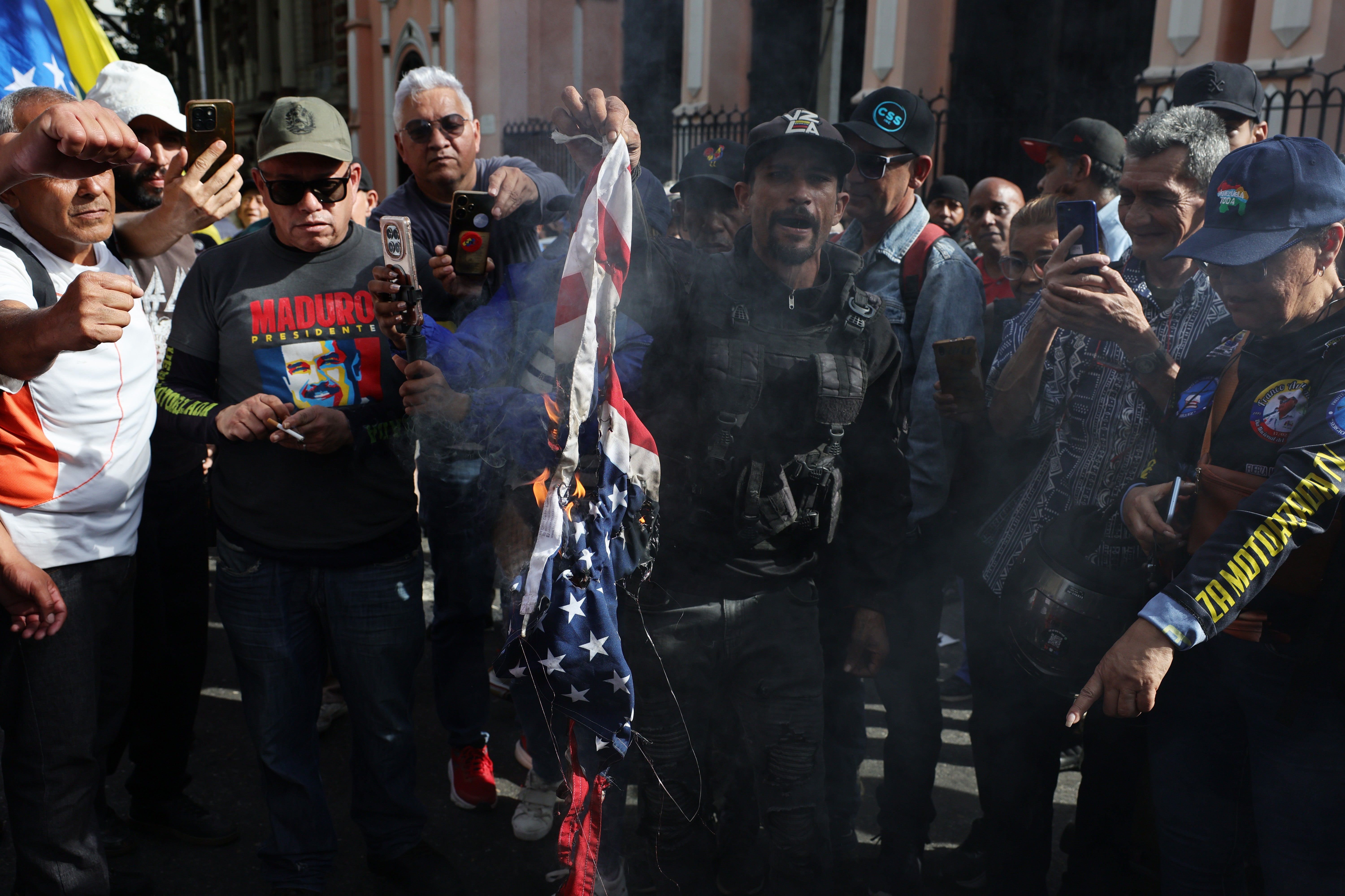 A man holds up a burning US flag in Caracas