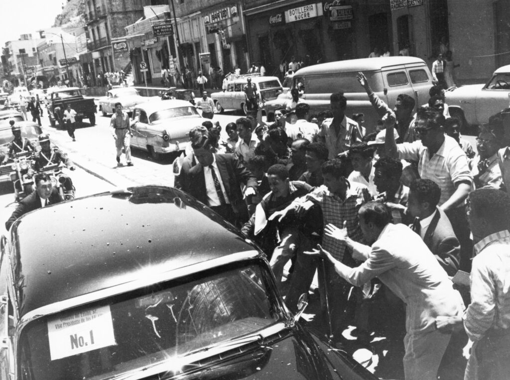 (Original Caption) 5/13/58-Caracas, Venezuela: Gesticulating rioters attack the limousine of Vice President Richard Nixon and his party here May 13th. The hoodlums smashed all but the front front and rear windows of Nixon's car (note sign "No. 1" on windshield), showering the occupants with glass. The Nixons sought refuge in the heavily-guarded embassy residence.