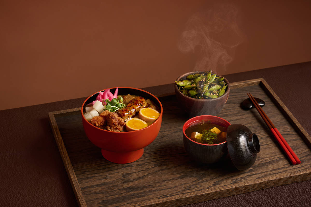 three bowls of food from a japanese set menu presented atop a wooden table