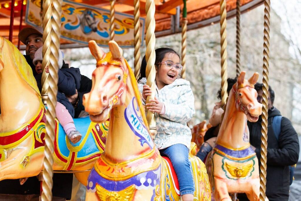 child sat on horse on carousel in manchester as part of super duper family festival