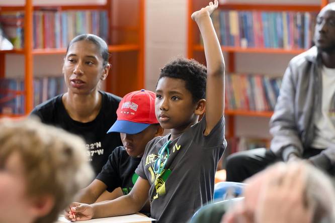 Child taking part in a workshop with his hand raised to answer a question