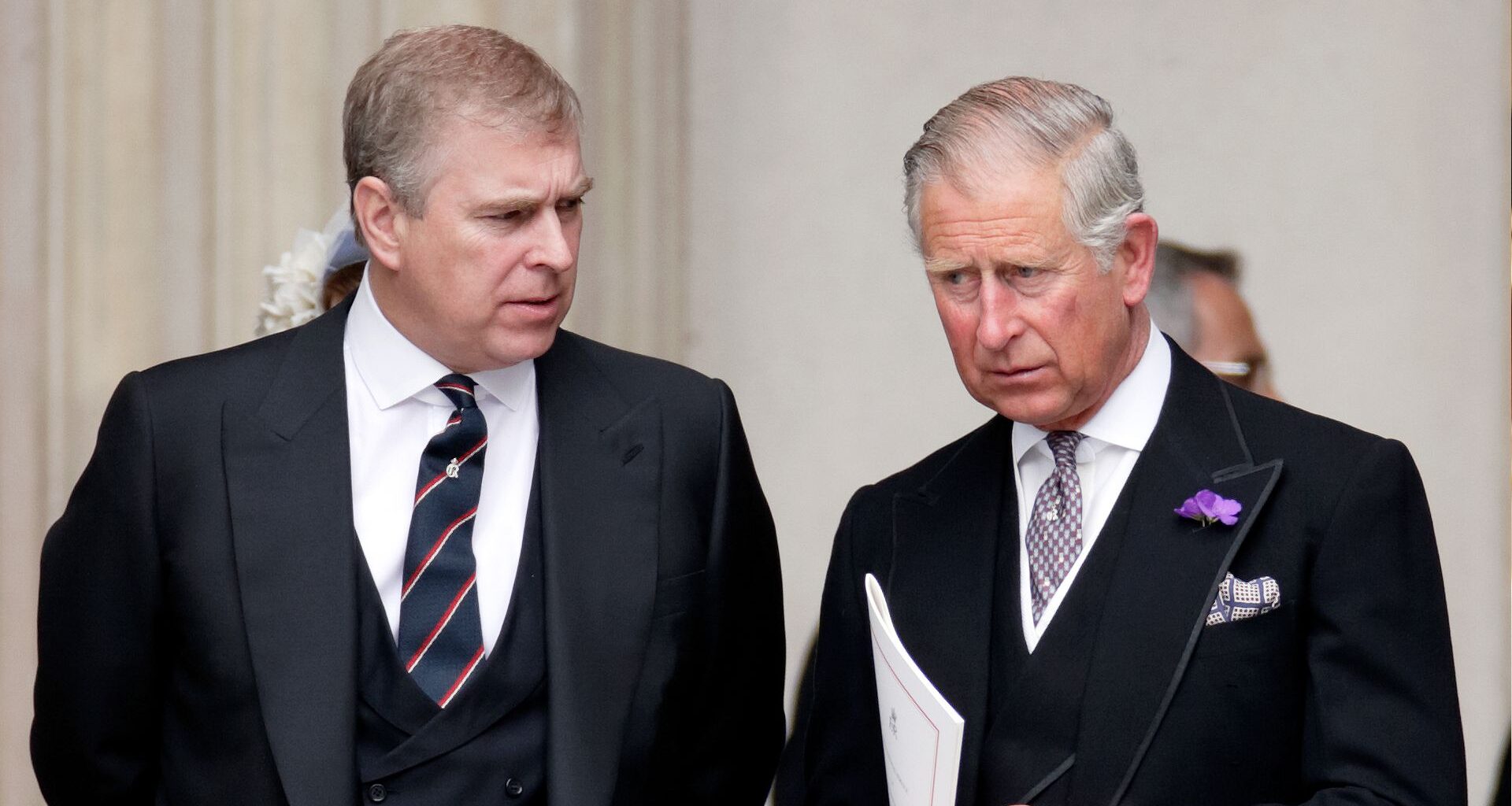 King Charles and Prince Andrew wearing dark suits, ties and serious expressions