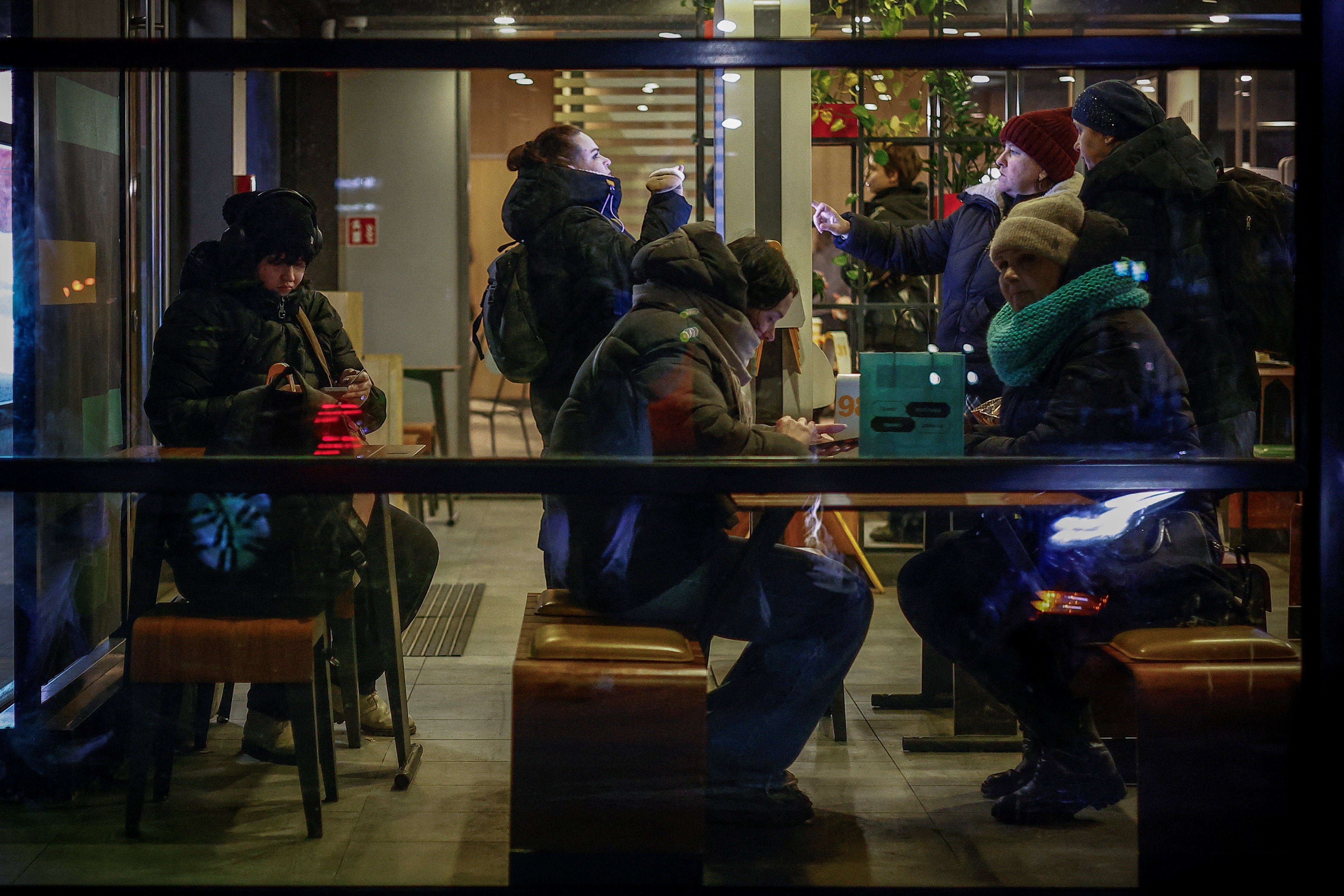 People warm up inside a restaurant in Kyiv on Friday