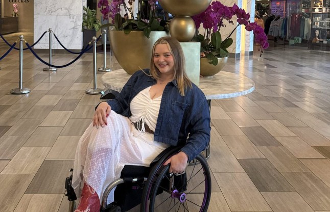Amy Pohl, who is smiling and in a wheelchair, in the middle of a hotel lobby.
