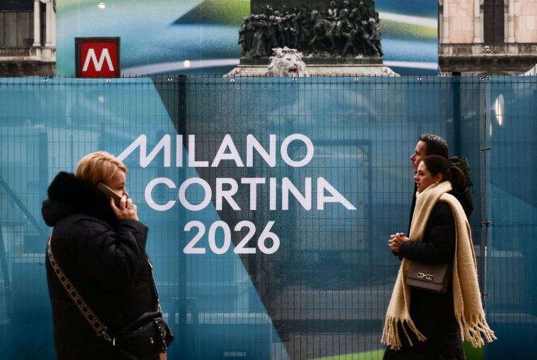 People walk past Milano Cortina 2026 Winter Olympic Games banners in Duomo's square in Milan on Januray 9, 2026. (Photo by Stefano RELLANDINI / AFP via Getty Images)